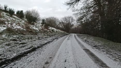 Driving-at-speed-on-snowy-rural-country-road-in-slippery-winter-conditions-on-frosty-morning