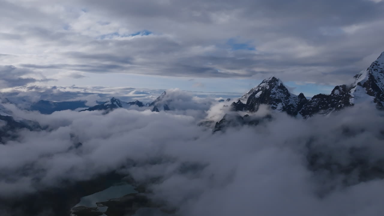 imágenes aéreas volando por encima de las nubes con cimas de montañas cubiertas de nieve y rocas en el fondo en perú