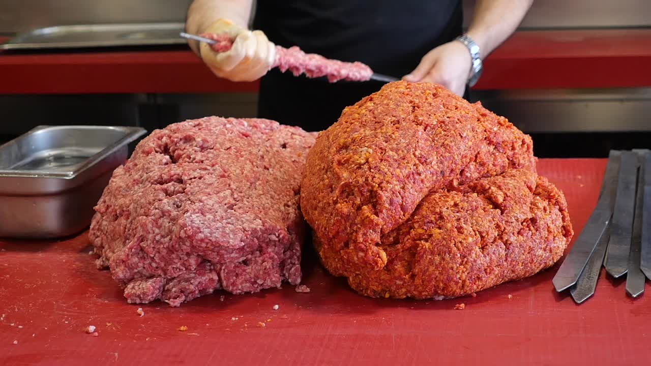 Chef's Hands Shaping Raw Ground Meat onto Kebab Skewers