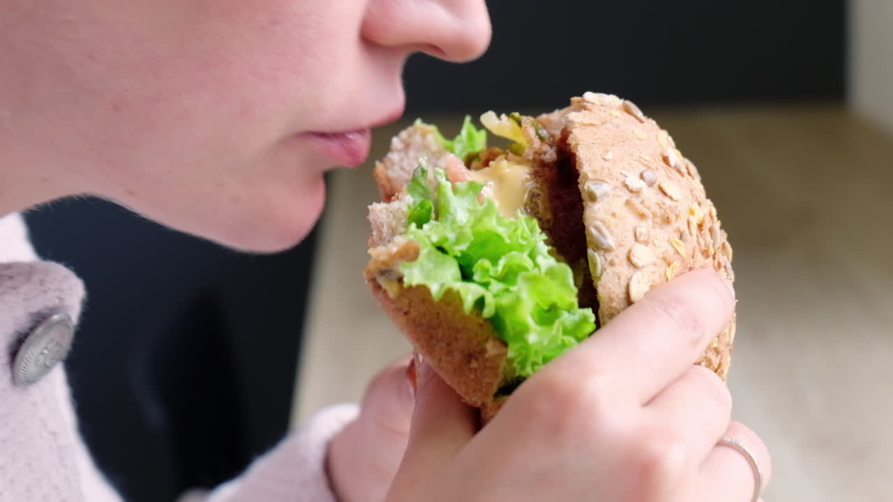 Close up of a woman eating a home made hamburger