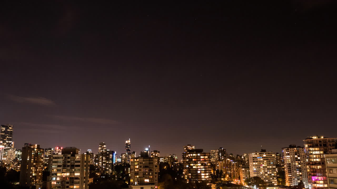 창문과  ⁇ 은 밤하늘에 빛을  ⁇ 는 현대적인 건물과 함께 도시 풍경