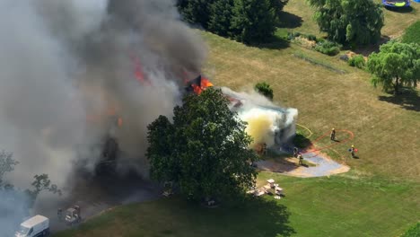 aerial view of a house fire with firefighters combating flames and smoke