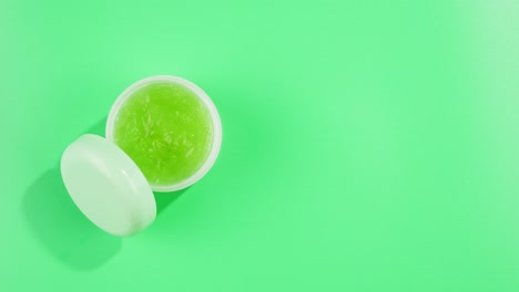 fresh ripe avocados with cream and essential oil on green background with mint mentol, make up cosmetics