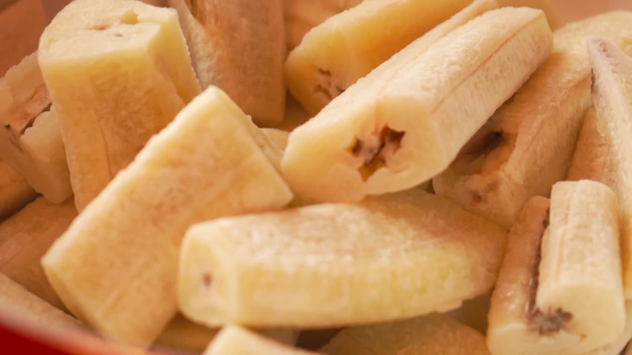 Steaming cooked green plantains inside a red pot. Traditional Latin American cooking. Ideal for culinary content, recipe visuals, or food culture documentation.