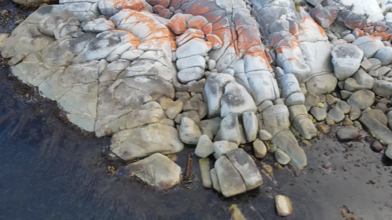 беспилотный летательный аппарат летит в сторону и панорамирует над пляжем бухты красных скал в пасмурный день