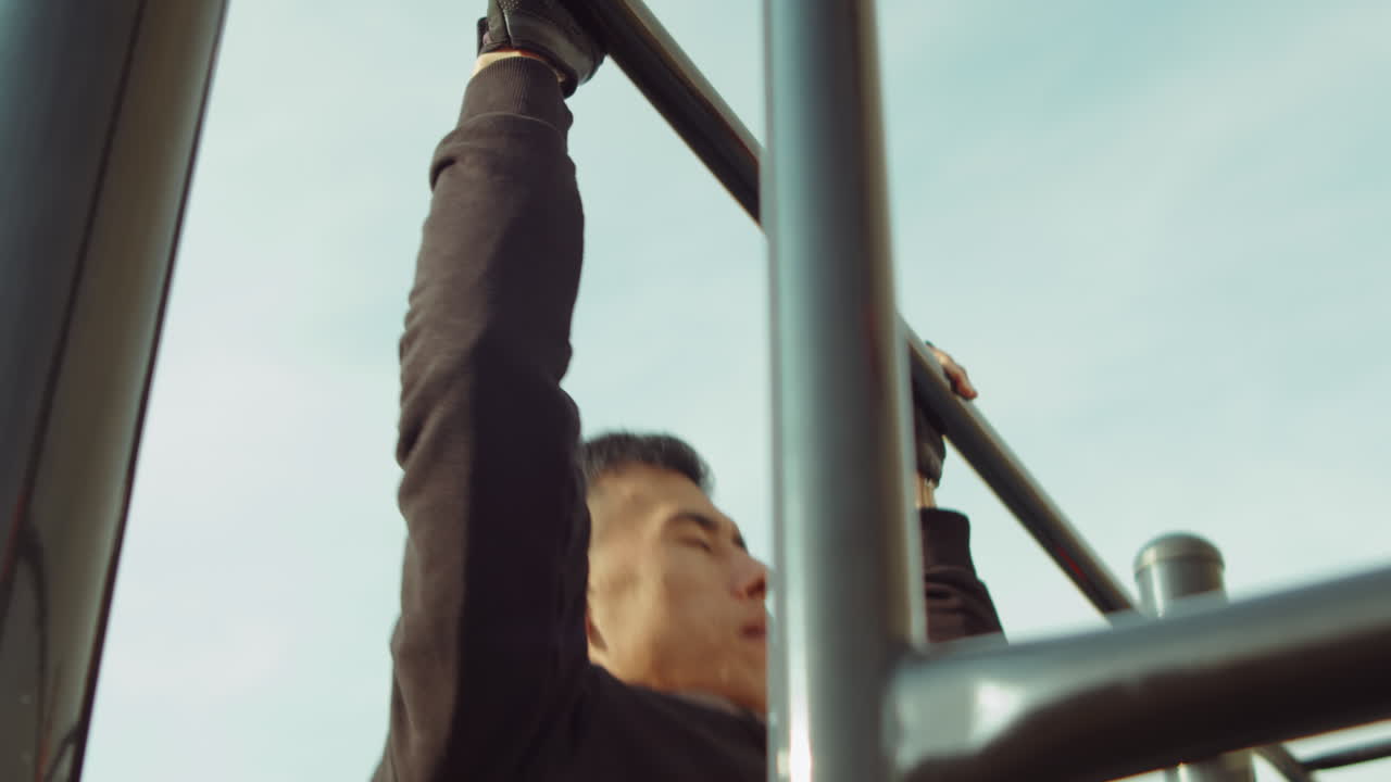 hombre fuerte haciendo pull-ups en una barra horizontal al aire libre