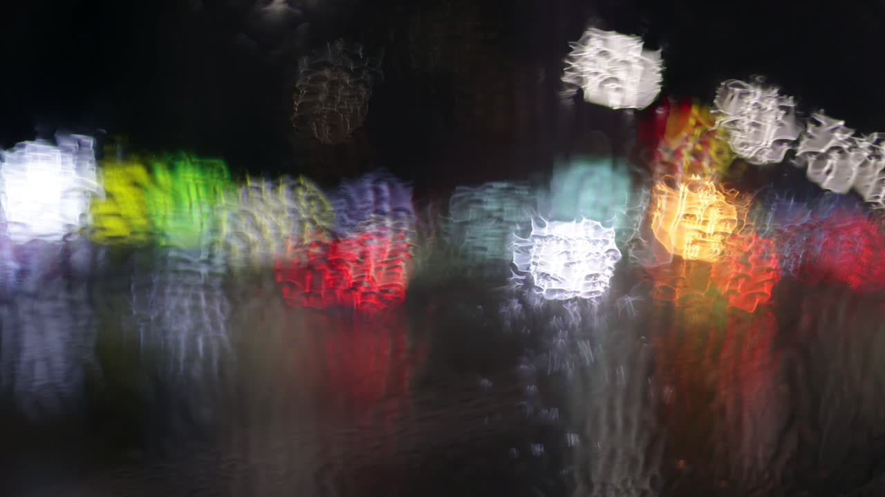 luces multicolores de la ciudad de la noche y coches que pasan a través de una ventana húmeda lluviosa. toma abstracta del tráfico de la ciudad por la noche bokeh. clima deprimente lluvioso. nueva york, estados unidos