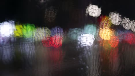 luces multicolores de la ciudad de la noche y coches que pasan a través de una ventana húmeda lluviosa. toma abstracta del tráfico de la ciudad por la noche bokeh. clima deprimente lluvioso. nueva york, estados unidos