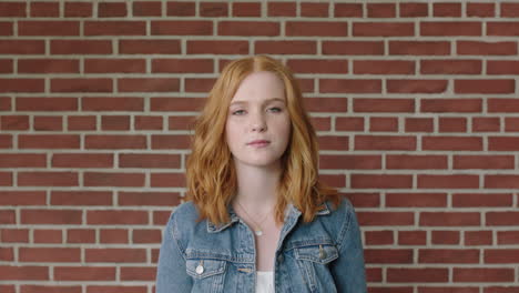 portrait-of-beautiful-red-head-woman-looking-serious-pensive-on-brick-wall-background