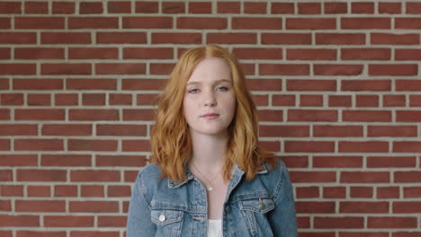 portrait of beautiful red head woman looking serious pensive on brick wall background