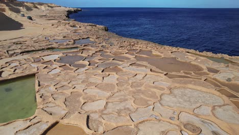 órbita baja de las salinas, la formación rocosa y el océano azul en la isla de gozo, malta
