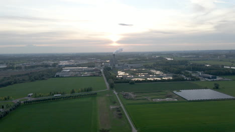 flying towards a distant smoking factory chimney against a setting sun