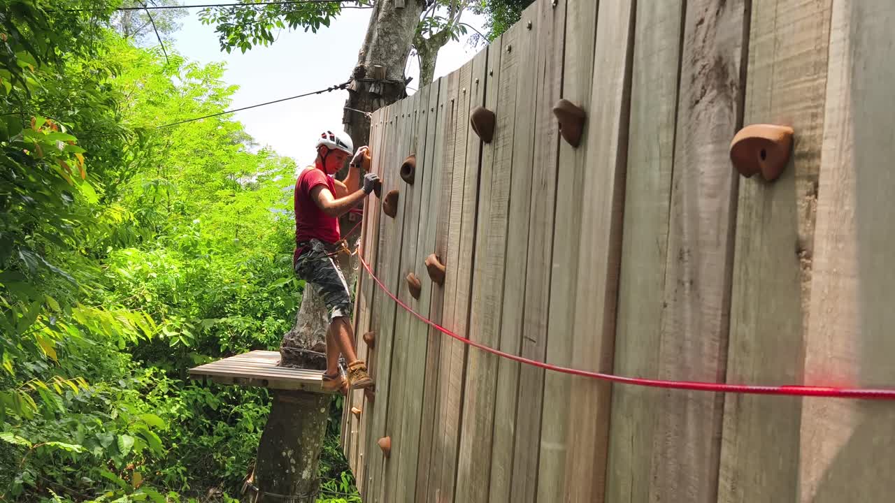 Man Climbing Wooden Wall in Adventure Park
