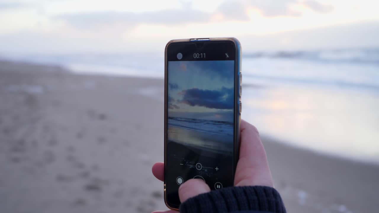 primer plano de una mujer joven haciendo un video con un teléfono inteligente en la hermosa playa de sylt