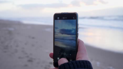 close up of a young woman making a video with a smartphone on at the beautif beach of sylt