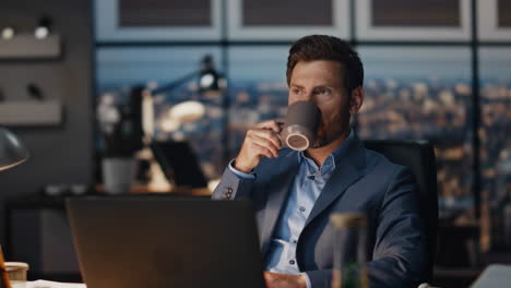 overworked guy drinking coffee at dark place closeup. office man enjoying tea