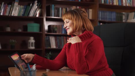 The woman is sitting in a chair at a table, with a photo frame placed on it