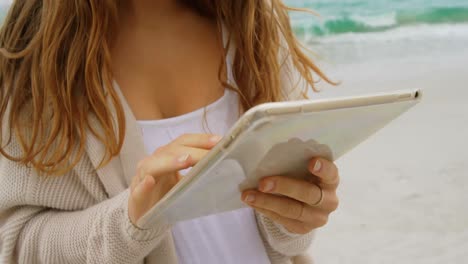 Vista-Frontal-De-Una-Mujer-Caucásica-Usando-Una-Tableta-Digital-En-La-Playa-4k