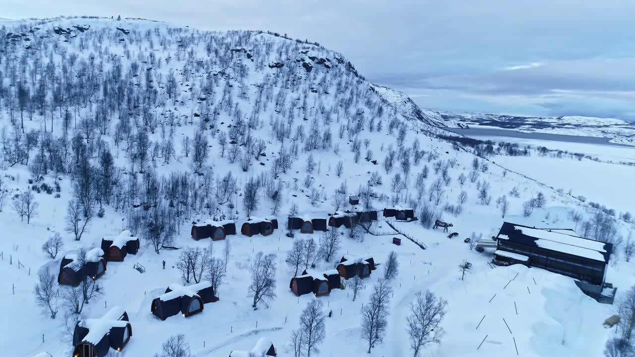 Lumipeitteiset hotellimökit valkoisen, puurivin reunustaman vuoren juurella