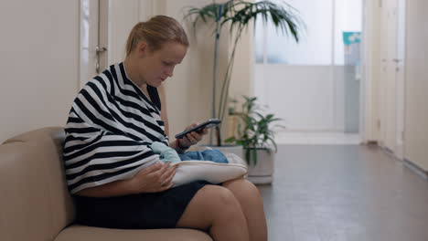 Mujer-Usando-Móvil-Y-Bebé-Lactante-En-El-Centro-De-Salud-Infantil.