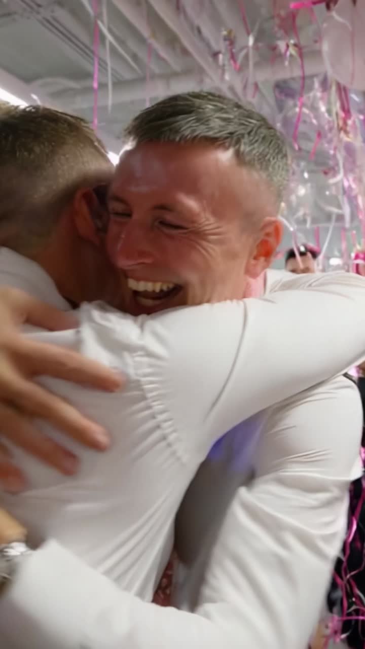 Joyful Celebration of Friendship: Two Men Embrace Amidst Festive Decor and Laughter, Surrounded by Friends in a Vibrant Atmosphere of Togetherness and Happiness
