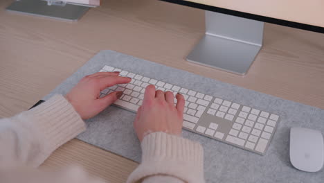 female employee working from home, typing on wireless keyboard on the table