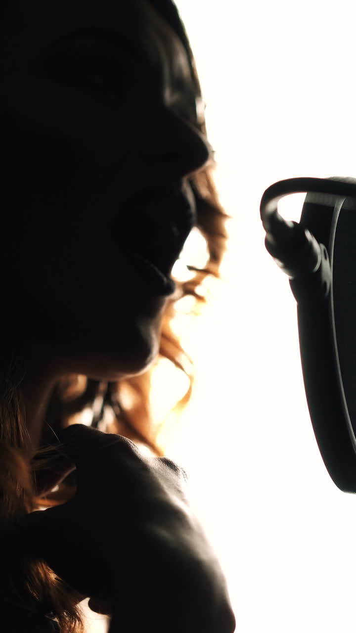 Young woman recording a song in a professional recording studio. Female vocal. Black and White. Vertical video