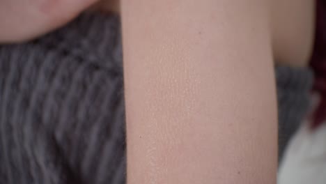 woman touches her arm with skin creme, close up view