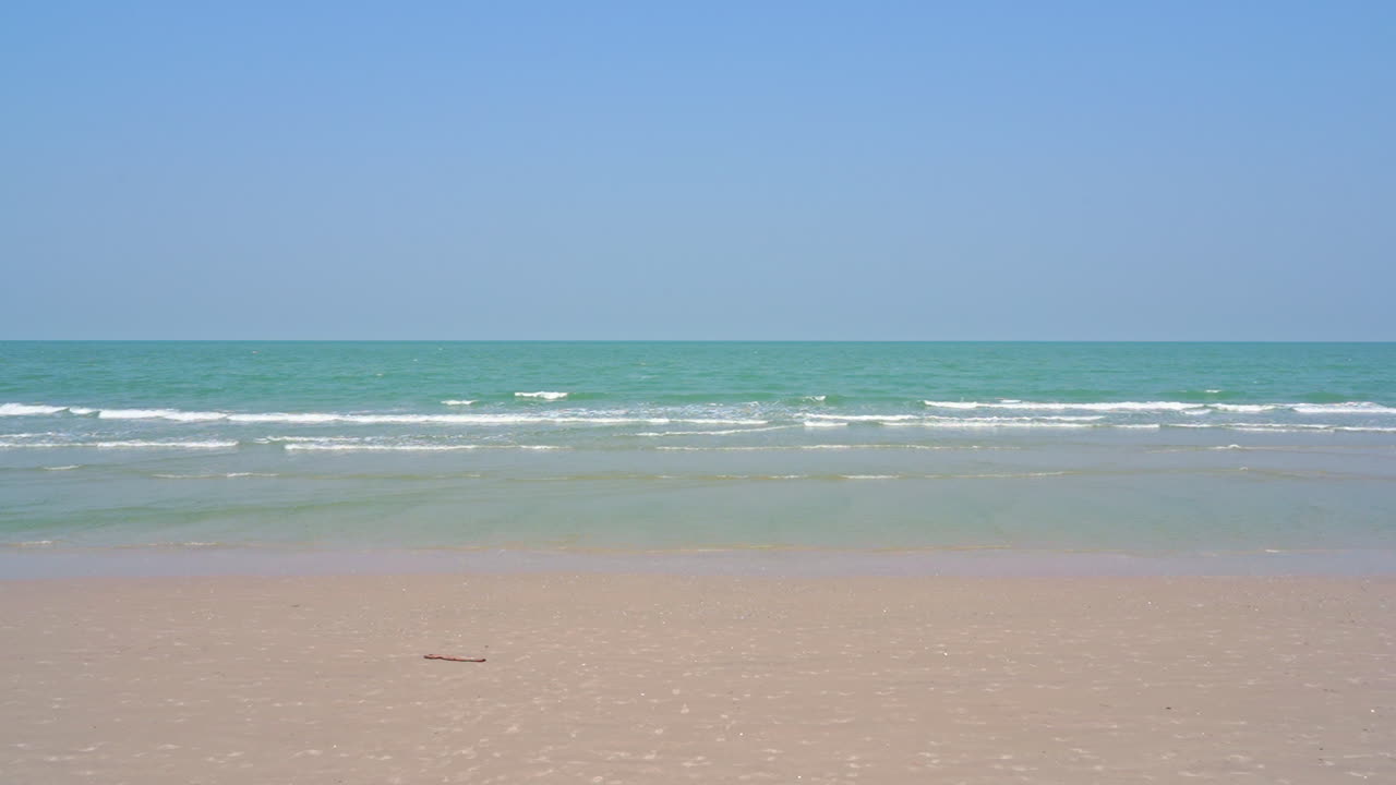Sea water low tide, waves slowly reaching sandy beach on clear sky sunny day