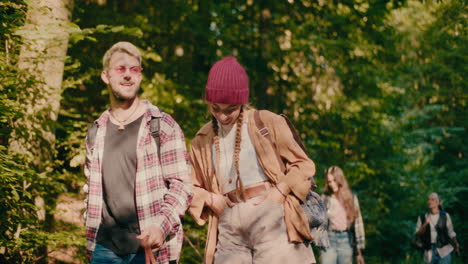 smiling woman talking with friend while exploring woods