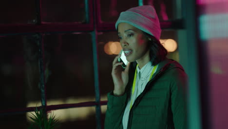 joven mujer de negocios afroamericana usando un teléfono inteligente charlando conversación de llamada telefónica discutiendo la fecha límite trabajando hasta tarde empresaria hablando por teléfono celular en la oficina por la noche