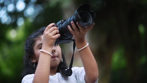 una linda niña asiática está tomando fotografías de la naturaleza y los árboles con una cámara réflex digital como un fotógrafo profesional