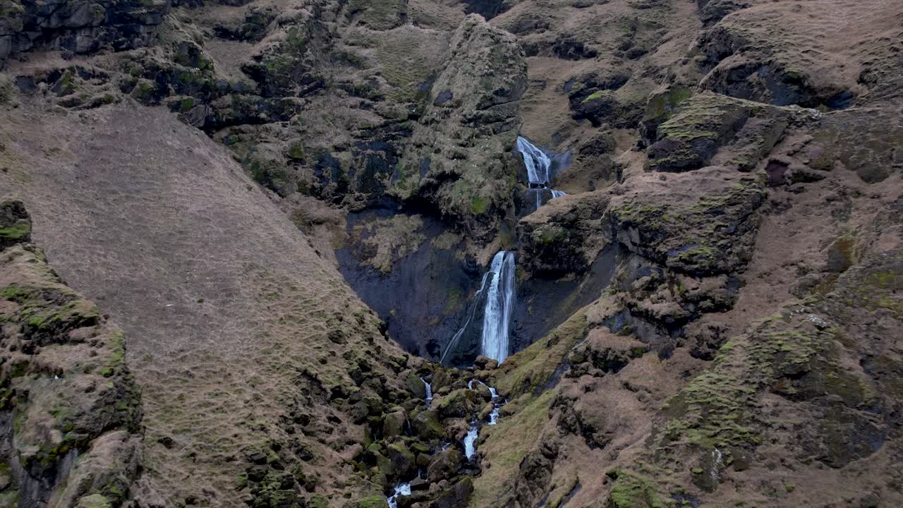 paisaje idílico de una pequeña cascada junto a vik en el sur de islandia - retirada aérea