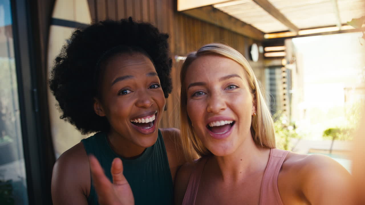 Tomada em Primeira Pessoa de Amigas Sorrindo Ao Ar Livre Em Casa Fazendo Chamada de Vídeo No Celular Juntas
