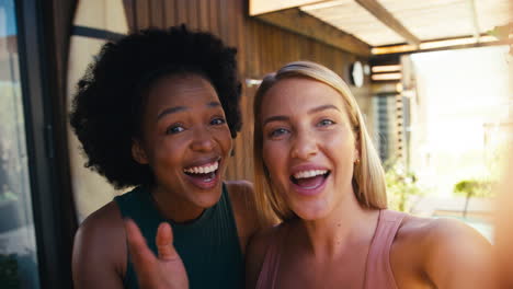 pov shot of smiling female friends outdoors at home making video call on  mobile phone together