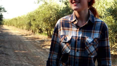 mujer sonriente caminando en la granja de olivos