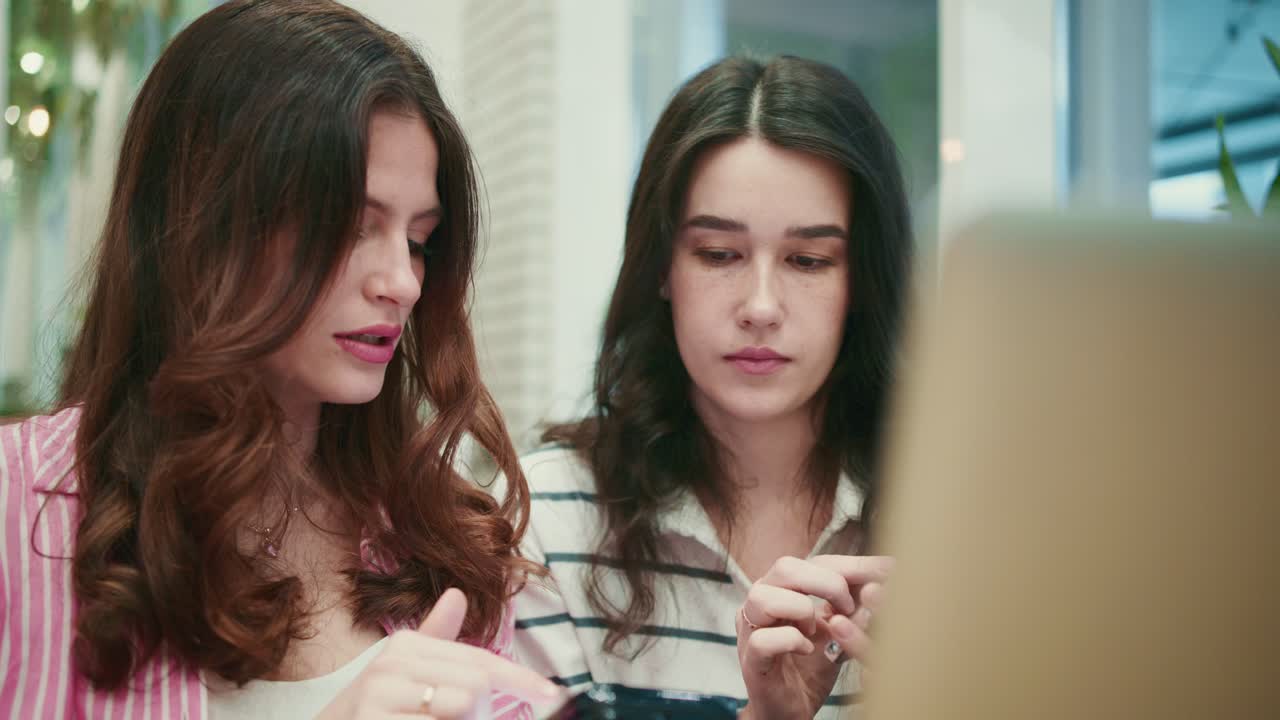 Two Young Women Discussing Content on Smartphone