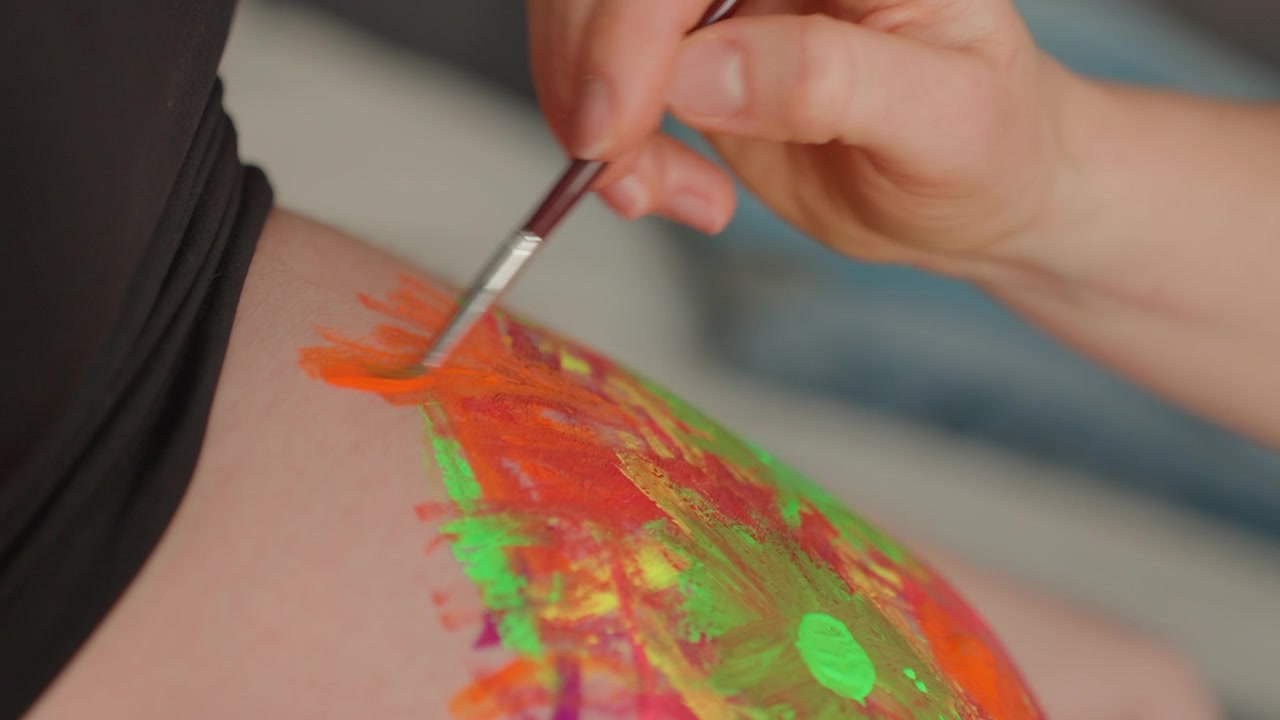 Close-up of Hand Painting Vibrant Fluorescent Colors on Skin