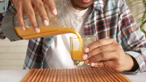 man pouring smoothie from blender into a glass