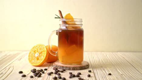 Ein-Glas-Eisgekühlter-Amerikanischer-Schwarzer-Kaffee-Und-Eine-Schicht-Aus-Orangen--Und-Zitronensaft,-Dekoriert-Mit-Rosmarin-Und-Zimt