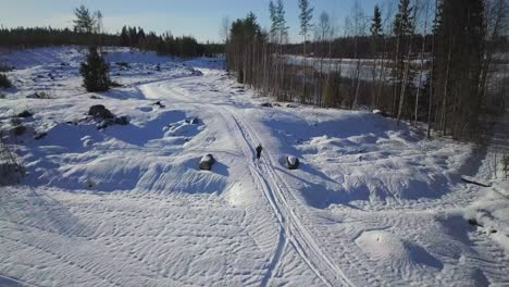 Aerial-view-of-man-running-fast-in-snow,-beautiful-landscape