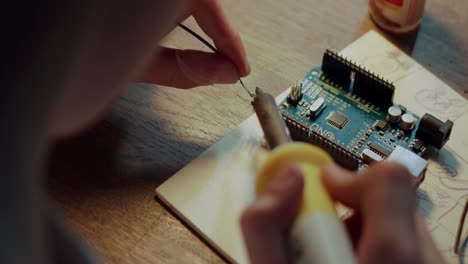 Teenager-is-attempting-to-repair-electronics-by-soldering-micro-particles-together