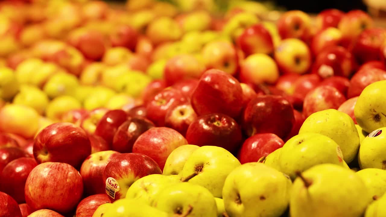 A colorful array of apples and pears in a market setting with warm lighting and dynamic camera movement