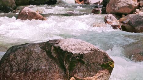 cinematic slo-mo shot of ganges river crystal clear water flowing downstream from mountains - falling sunshine on rocks in harshal village of uttarakhand