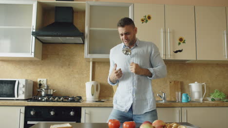 man singing and dancing in kitchen with a spoon