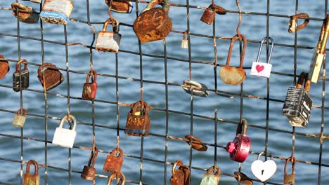 Love-Lockets-Secured-on-a-Fence-with-Blurred-Ocean-in-the-Background,-San-Francisco,-California,-USA