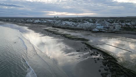 Drones-Aéreos-Vuelan-Sobre-El-Paisaje-Marino,-La-Costa-De-Las-Grutas-Rio-Negro-Argentina-Vista-Al-Mar-Y-La-Ciudad,-Cielo-Patagónico-Azul