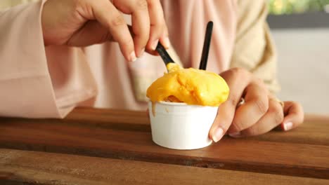 women eating mango flavor ice cream on table