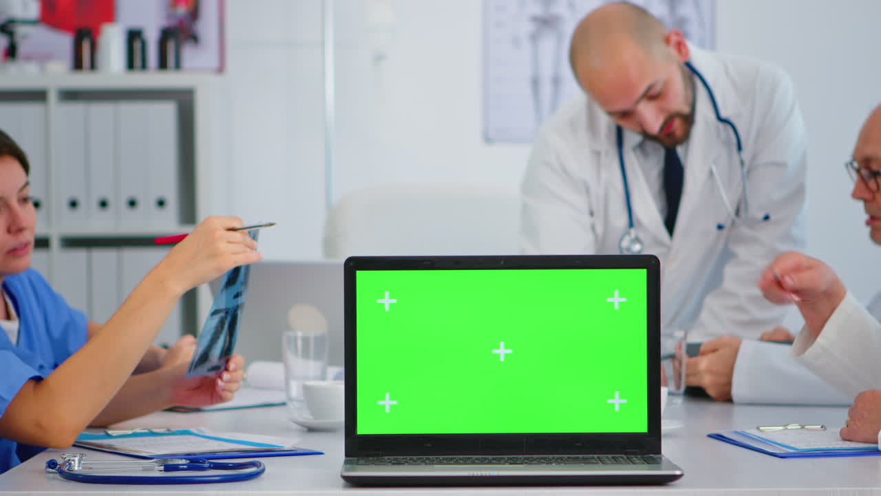 equipo de médicos colocando una computadora portátil con pantalla verde frente a la cámara