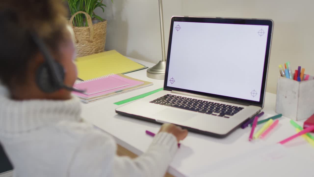 African american girl sitting at table and having video call